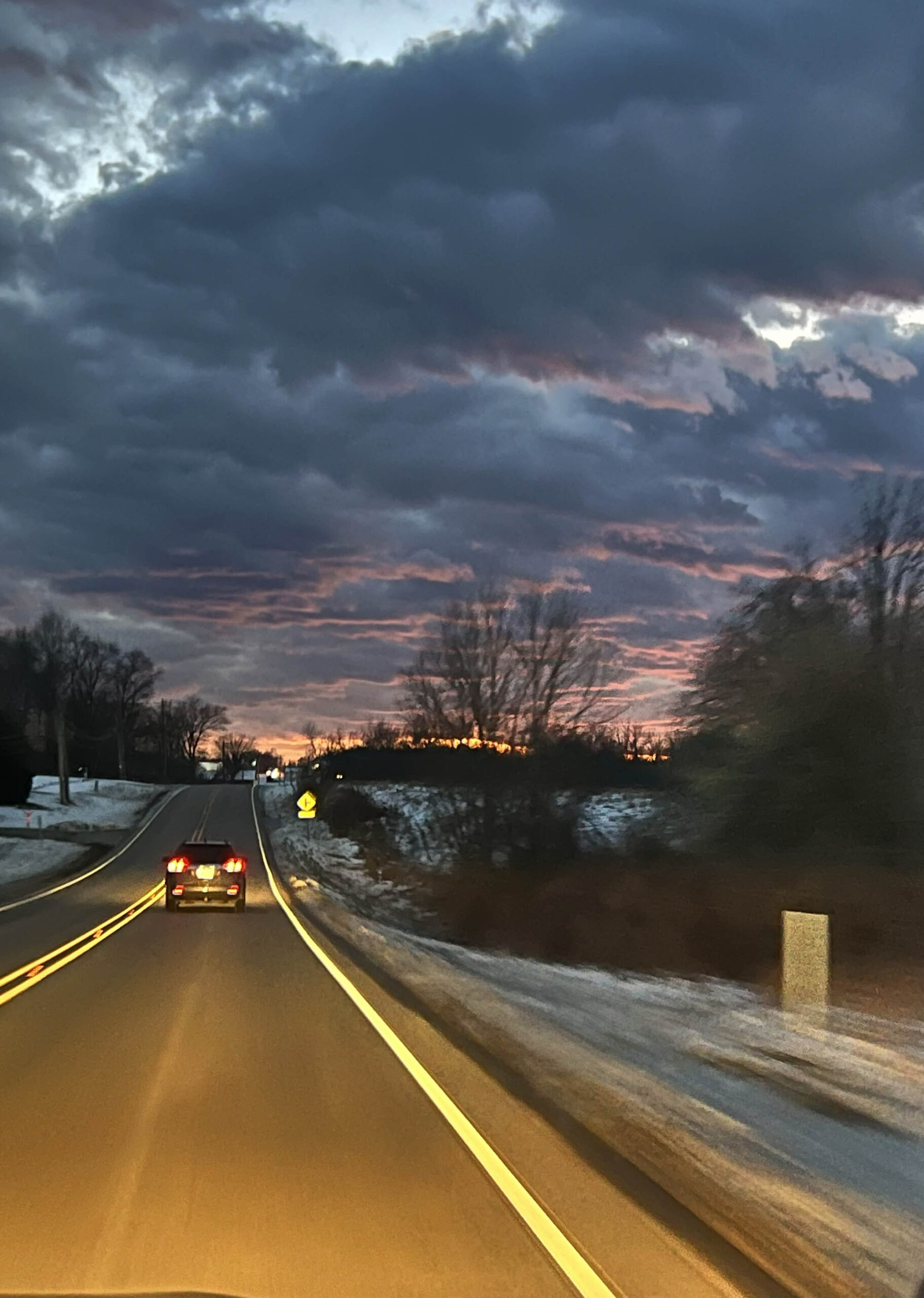 A car drives along a winding road at dusk