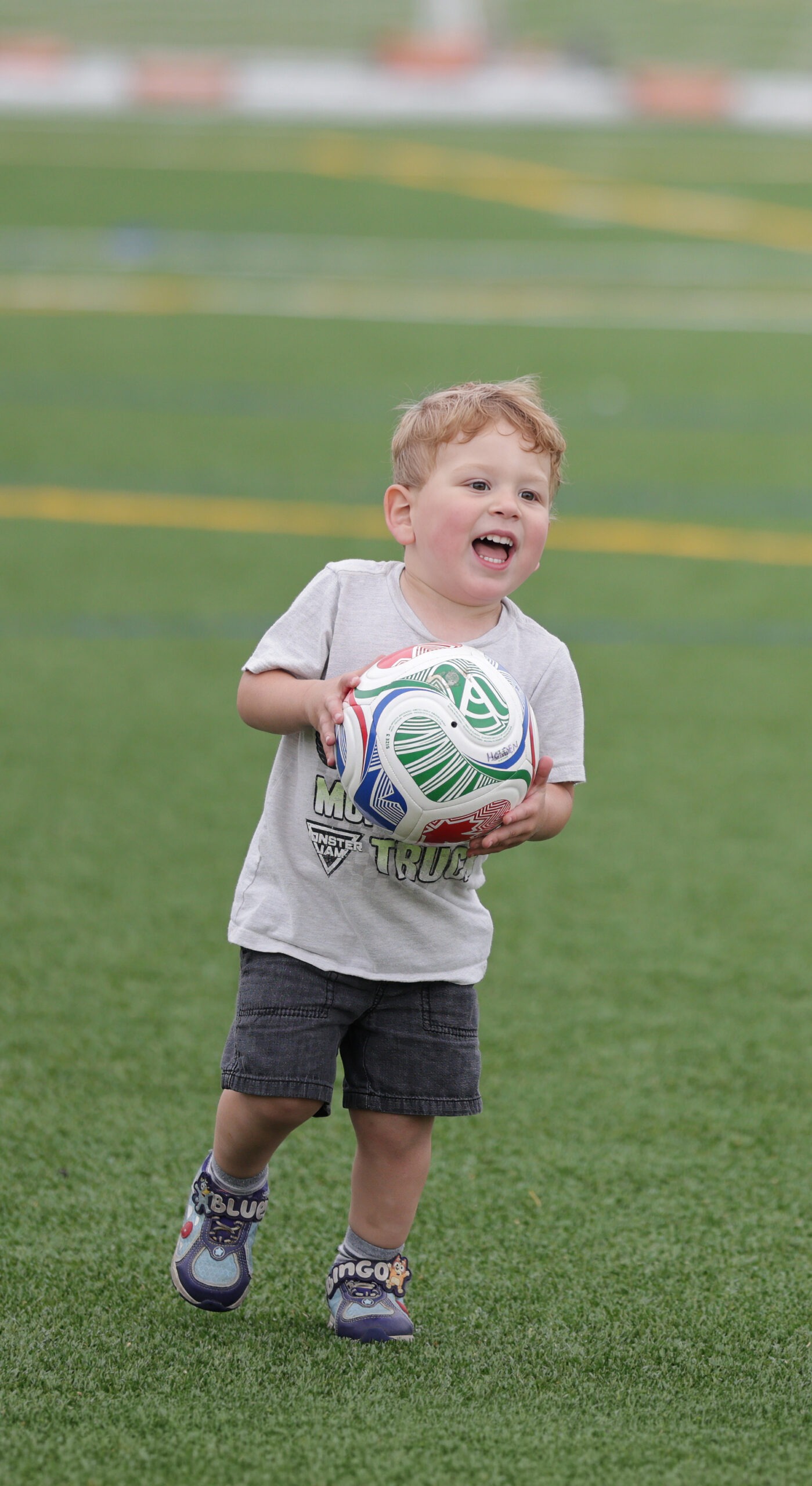 Young child joyfully runs on a grassy field,